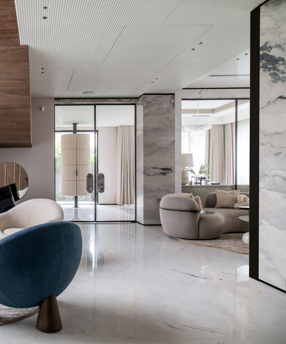 Tall curtained windows framing a contemporary interior with marble and upholstered seating