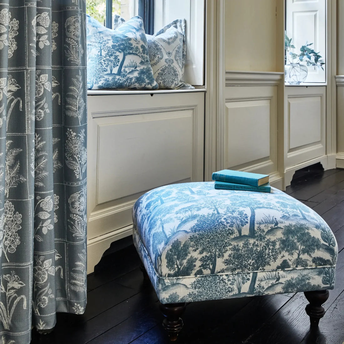 Coordinated blue patterned curtains and upholstered footstool