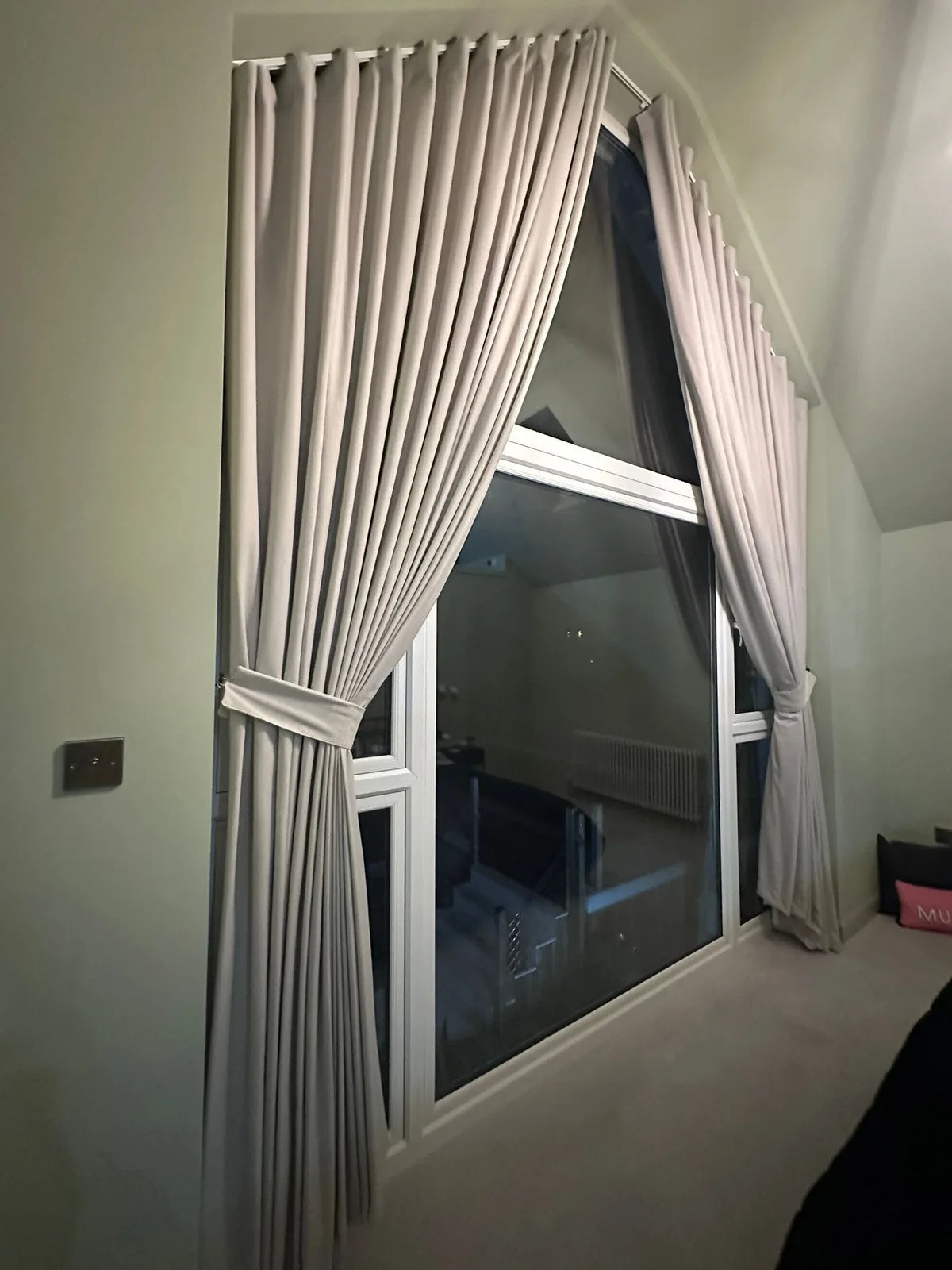 Pale full-length curtains framing tall gable-end glazing