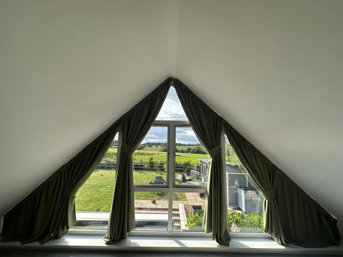 Olive curtains and matching tiebacks framing triangular glazing